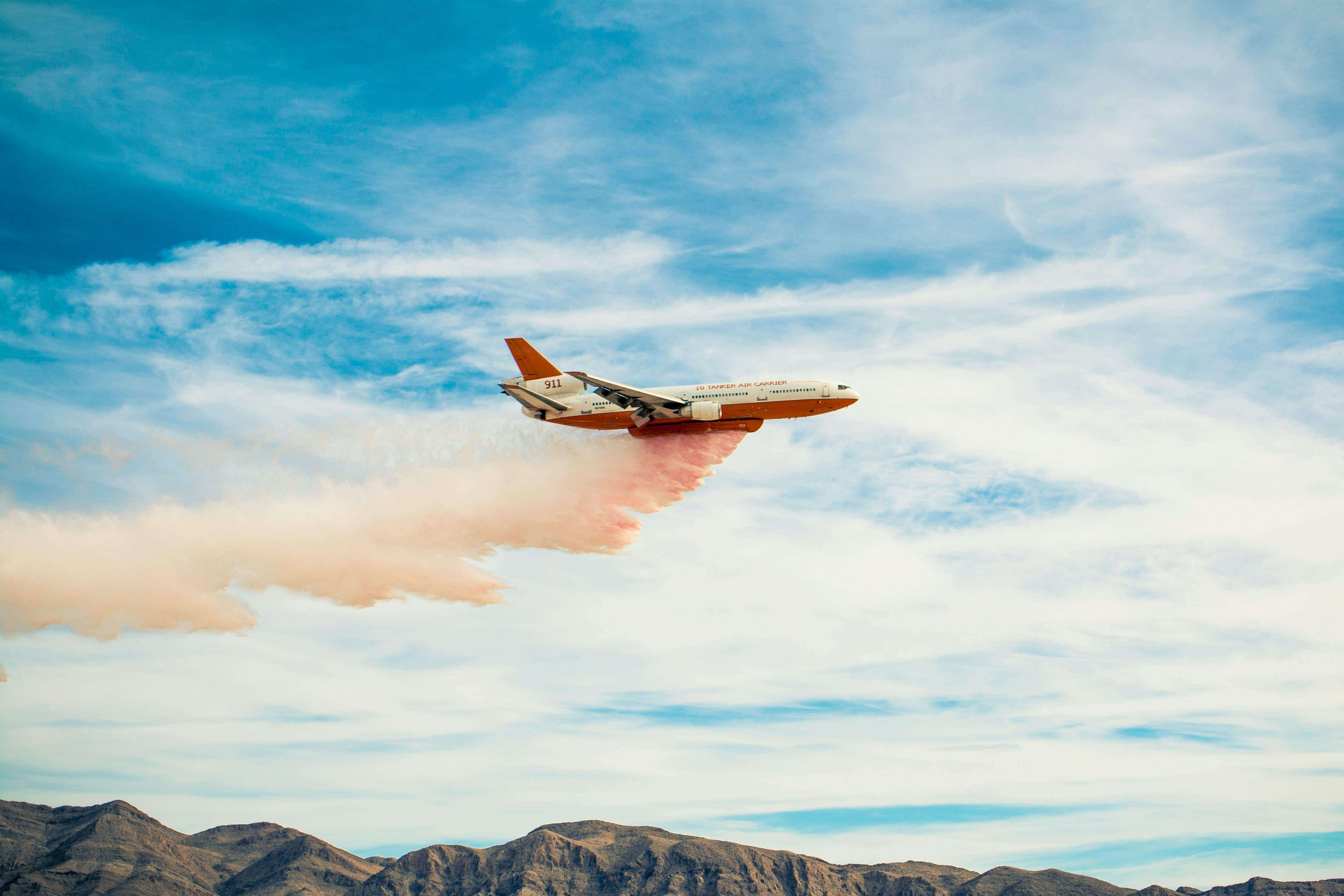 white plane spreading pink smoke